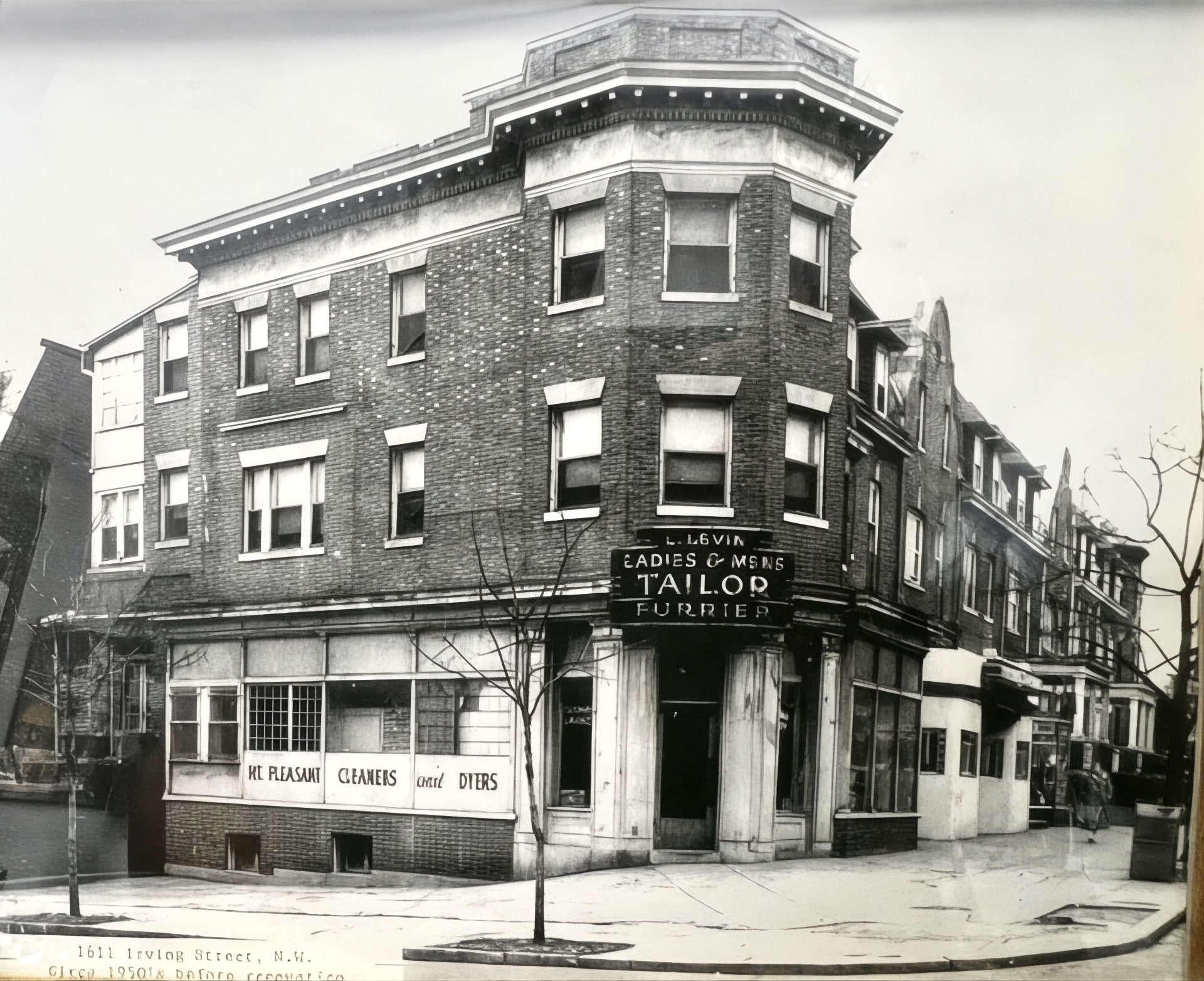 Black-and-white photo of the Mount Pleasant corner building in the 1950s, before it was Irving Wine & Spirits — then home to 'L. Levin Ladies & Mens Tailor / Furrier' and 'Mt Pleasant Cleaners & Dyers,' three stories of brick on a quiet street corner.