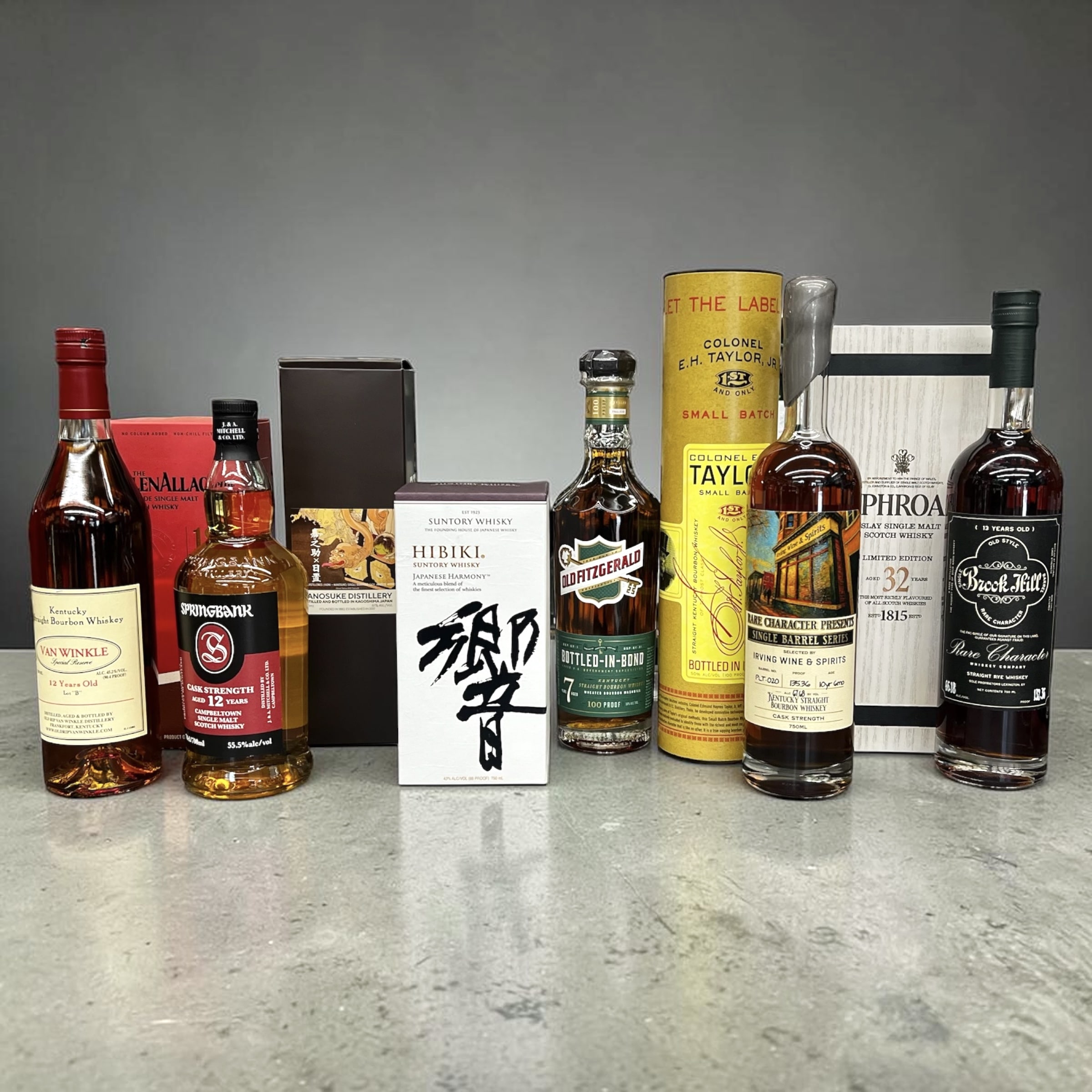 A lineup of sought-after whiskies on the counter at Irving Wine & Spirits — Pappy Van Winkle 12 Year 'Lot B,' Springbank 12 Cask Strength, Hibiki Japanese Harmony, Old Fitzgerald Bottled-in-Bond, Colonel E.H. Taylor Small Batch, a Rare Character single-barrel store pick, Laphroaig 32 Year, and Brook Hill 13 Year Rye.